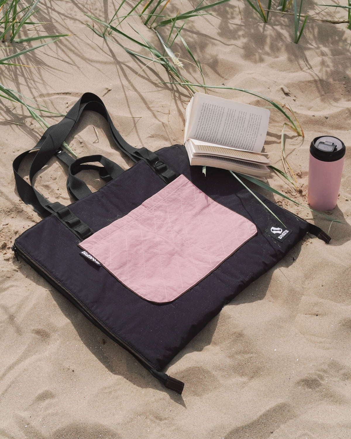 Dusty pink 3-in-1 dog travel bed and bag on sandy beach with book and bottle – waterproof and foldable dog mat by BONES