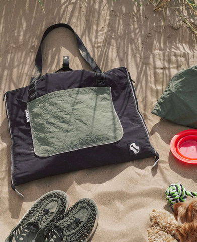 Close-up of sage green waterproof dog travel bed fabric with quilted stitching, book and dog fur – foldable dog mat by BONES